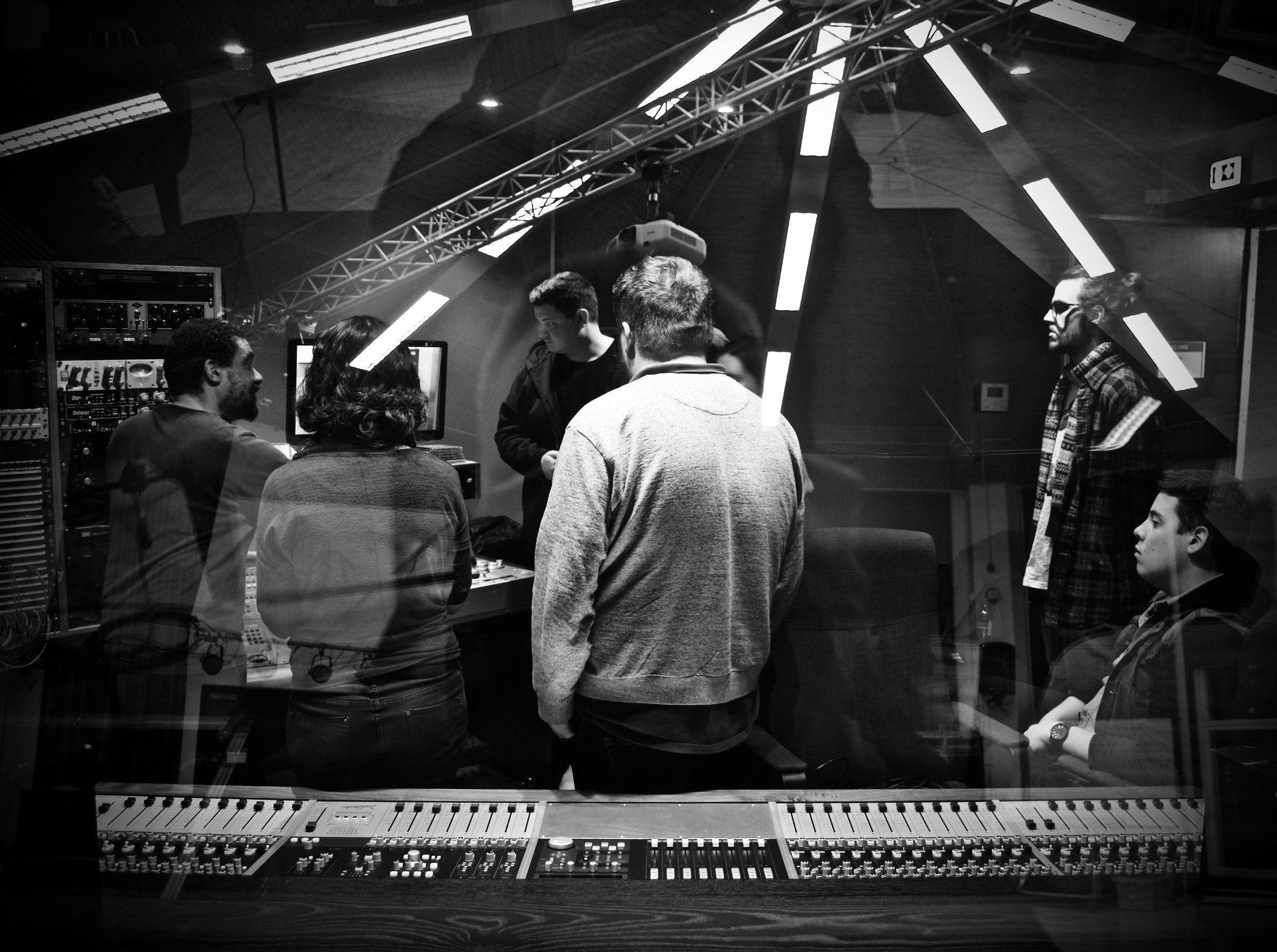 A group gathered at the console in the control room, in black and white