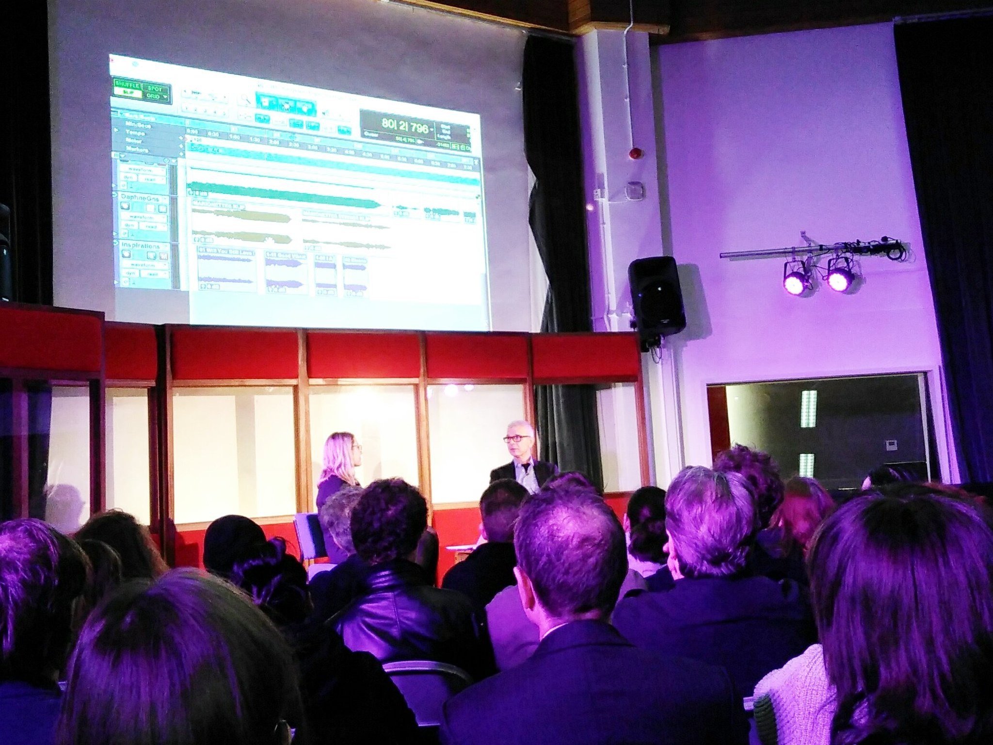 The audience watching Tony Visconti and Leah Kardos on stage, a session projected on the screen above them