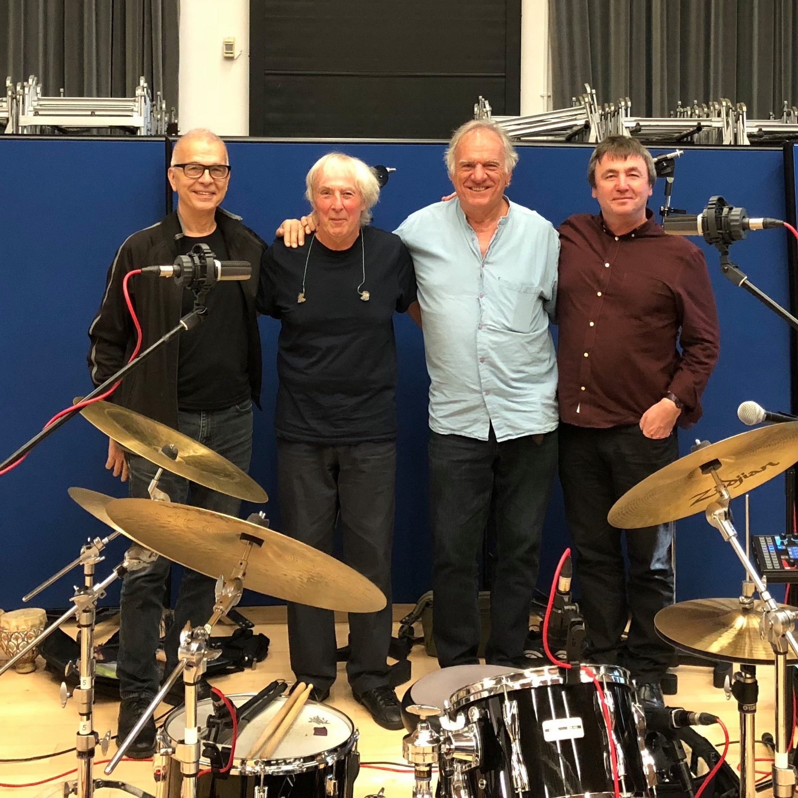 Tony Visconti, Gerry Conway, Ralph McTell and Frank Gallagher standing together in the live room behind a drum kit
