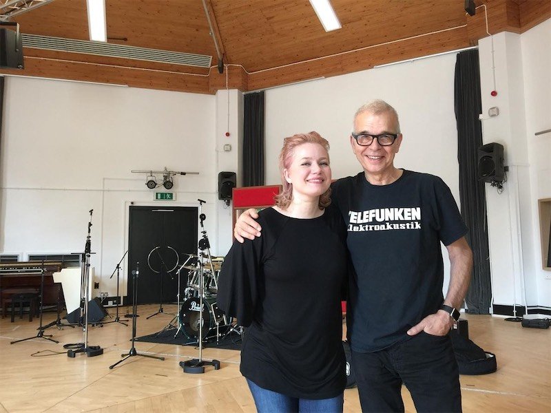 Mary Epworth and Tony Visconti posing in the live room, drums and organ visible in the background