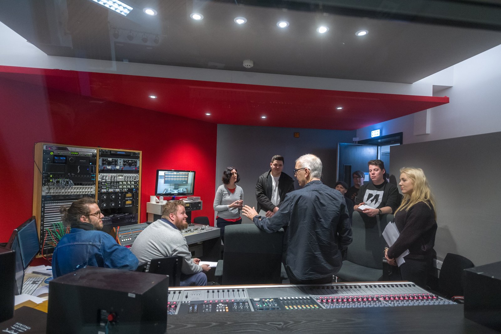 A group in discussion in the red-walled control room